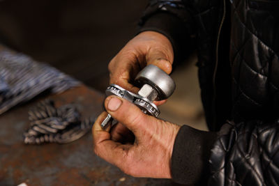 Dirty hands of caucasian car technician holding silver tool and wrench