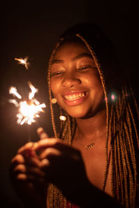 Portrait of woman holding illuminated string lights at night