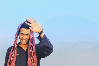 Portrait of smiling man gesturing against sky