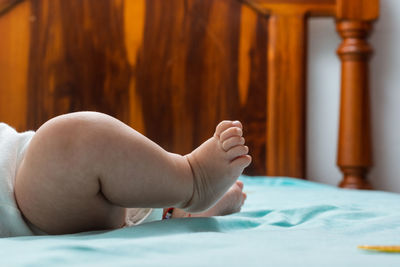 Close-up detail of the feet of a latina baby girl lying on a bed with blue sheets. 