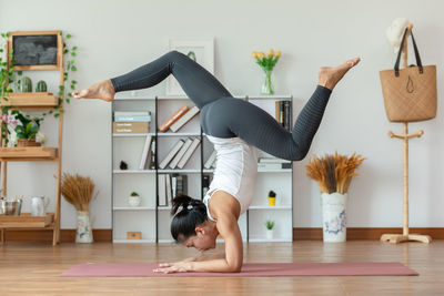 Full length side view of woman sitting on floor at home