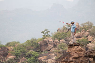 Man pointing while standing on rock