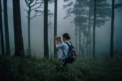 Full length of man photographing through camera in forest