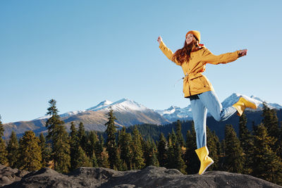 Low angle view of man jumping on mountain against sky