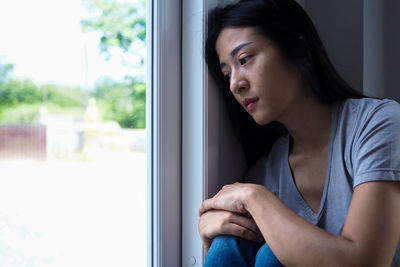 Portrait of woman looking through window