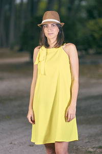 Portrait of woman standing against trees on field