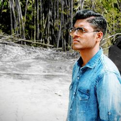 Young man wearing sunglasses against bamboo groves