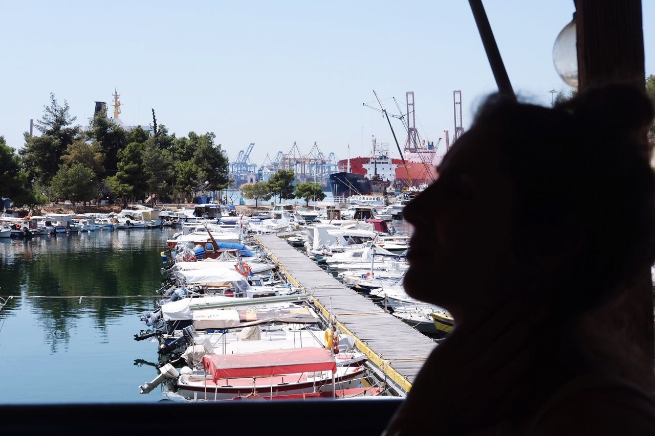 nautical vessel, mode of transport, transportation, boat, moored, clear sky, real people, day, harbor, water, built structure, outdoors, sailboat, architecture, building exterior, sky, tree, mast, travel destinations, one person, yacht, men, sailing, city, nature, people