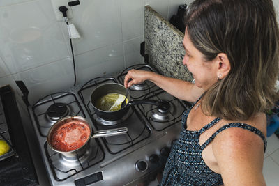 Side view of young woman preparing food at home