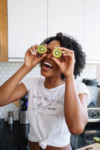 Beautiful black woman with curly hair holding kiwis in her hands