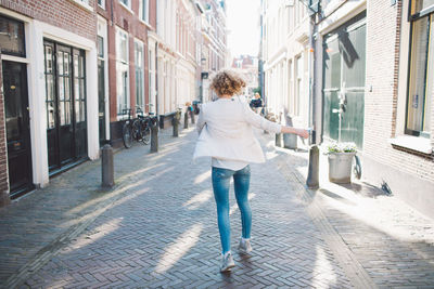 Rear view of woman walking on street amidst buildings