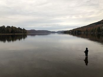 Man in lake against sky