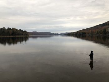 Man in lake against sky