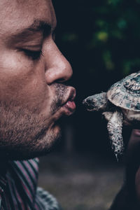 Side view of man kissing tortoise