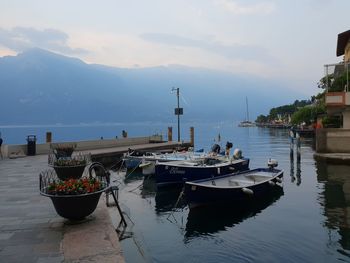 Sailboats moored at harbor against sky