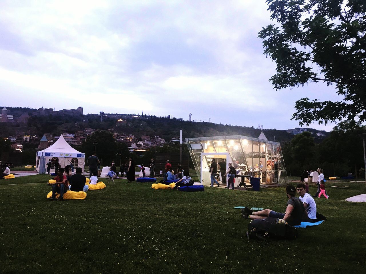 PEOPLE SITTING IN PARK AGAINST SKY