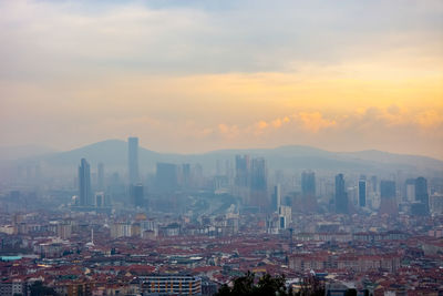 Modern buildings in city against sky during sunset