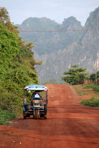 Vehicle parked on road by trees against mountains