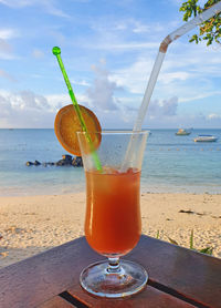 Close-up of drink on table at beach against sky