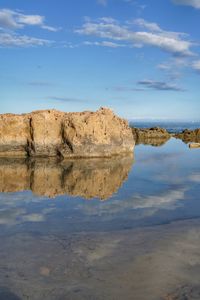 Rock formations on beach against sky