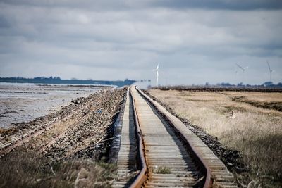 Railroad tracks on field against sky