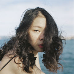 Close-up portrait of young woman against sea