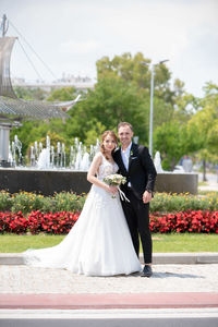 Portrait of smiling bridegroom standing by plants outdoors