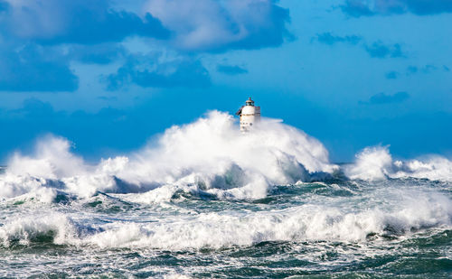 View of waves splashing on sea against sky