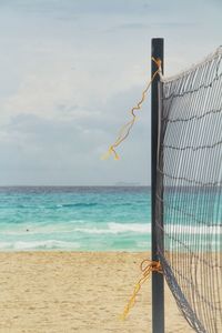 Close-up of volleyball net near sea against sky