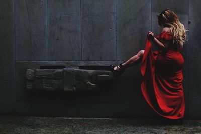 Side view of woman standing against wooden wall