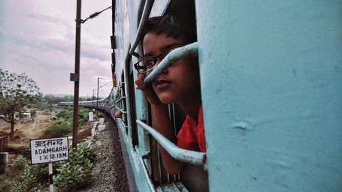 Close-up of boy looking through train window