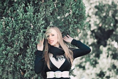 Portrait of young woman standing against plants