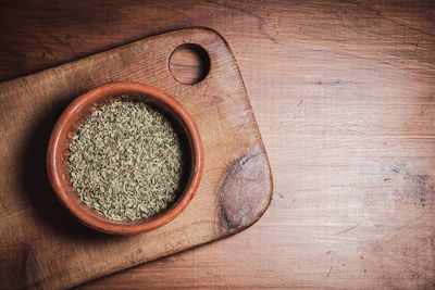 Overhead view of pot with oregano on wooden table