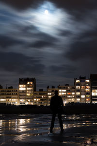 Silhouette of man walking on illuminated city at night