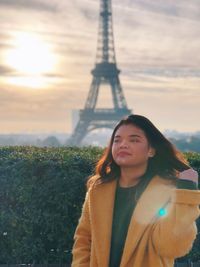 Smiling young woman looking away standing with eiffel tower in background