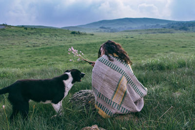 Woman with dog on field against sky