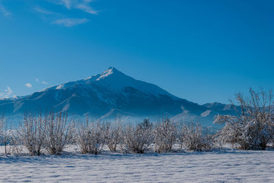 Scenic view of snowcapped mountains against blue sky