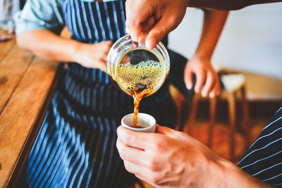 Midsection of man pouring wine in glass