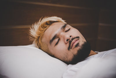 Close-up of young man sleeping on bed at home