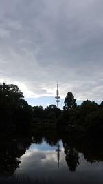 Reflection of trees in lake against cloudy sky