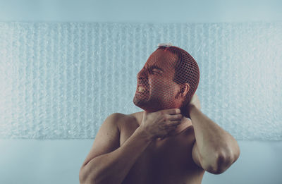 Man strangling neck with netting against wall