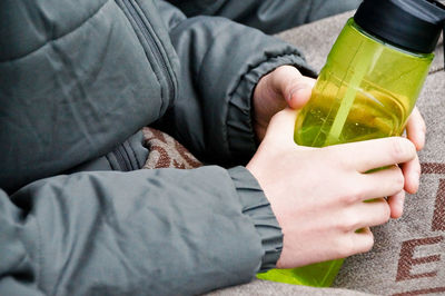 Midsection of man holding bottle