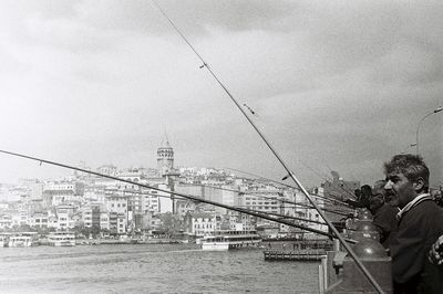 People fishing in sea against sky