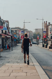 Rear view of man walking on street in city