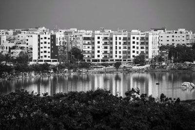 Buildings by lake against sky in city