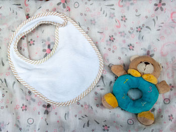 High angle view of baby bib and stuffed toy on fabric