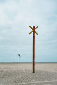 Cross on beach against sky