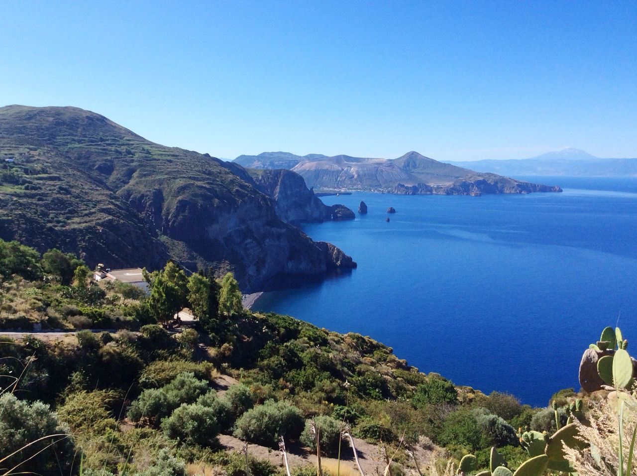 mountain, water, blue, clear sky, tranquil scene, scenics, tranquility, sea, beauty in nature, copy space, mountain range, nature, high angle view, lake, idyllic, coastline, landscape, tree, day, calm