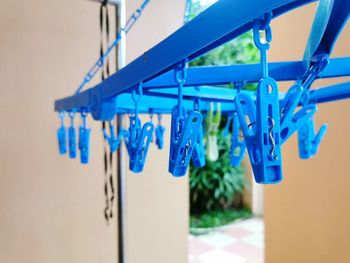 Close-up of clothespins hanging against blue wall