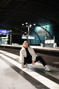 Portrait of woman crouching at railroad station